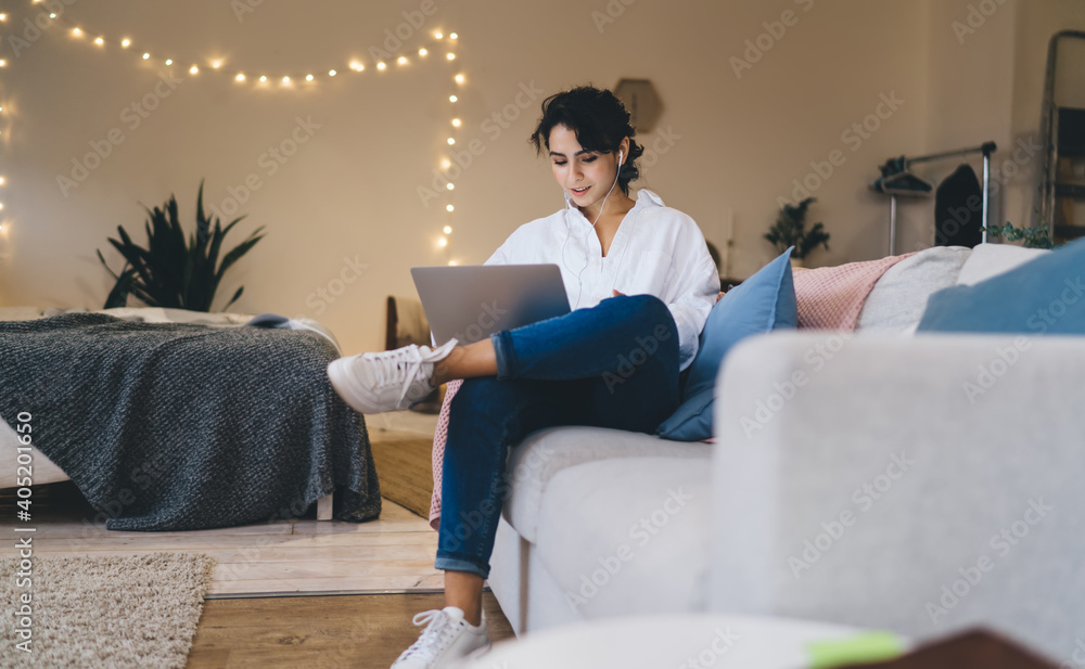 Wall mural Content woman using laptop on cozy couch