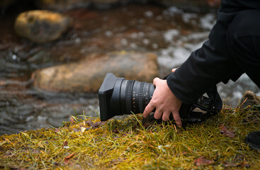 Close up view of a photo video mirrorless camera held in hand by a male photographer in nature...