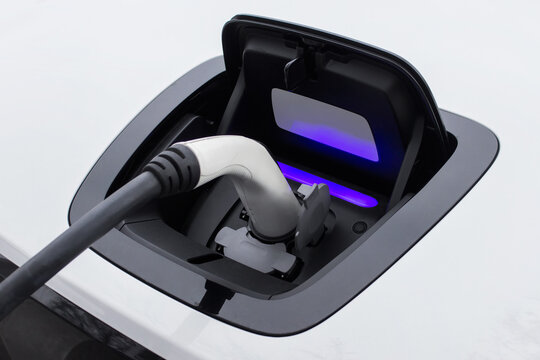 Closeup of a socket of charging electric car with plugged in charger from electric station.