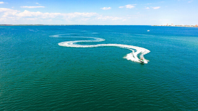 Aerial shot of the ocean with a personal watercraft sailing on a sunny da