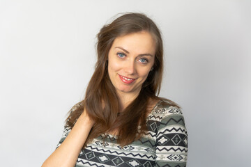 Naklejka premium studio portret of young beautiful smiling girl with long brown hair wearing white grey patterned dress on a light grey background 
