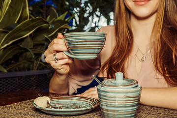 Midsection of lady holding cup of coffee in hands in an air in cafe