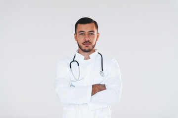 Medic in uniform. Young handsome man standing indoors against white background