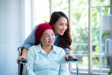 Asian young daughter smile and stand closely to her survivor mother from cancer by encouraging and...