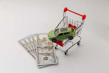 Toy car in a shopping basket and dollar banknotes.