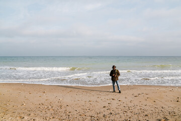 Focused handsome photographer walking with digital camera