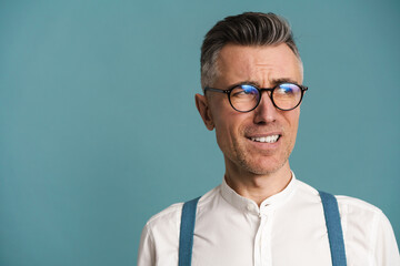 Confused grey-haired man in eyeglasses grimacing and looking aside