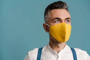 Caucasian grey-haired man in face mask posing and looking aside