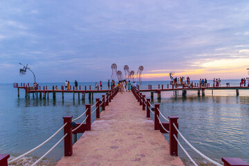 Fototapeta premium Sunset in Phu Quoc beach with nice view. Tourists, sunbeds and umbrellas on beautiful day in Sanato beach.