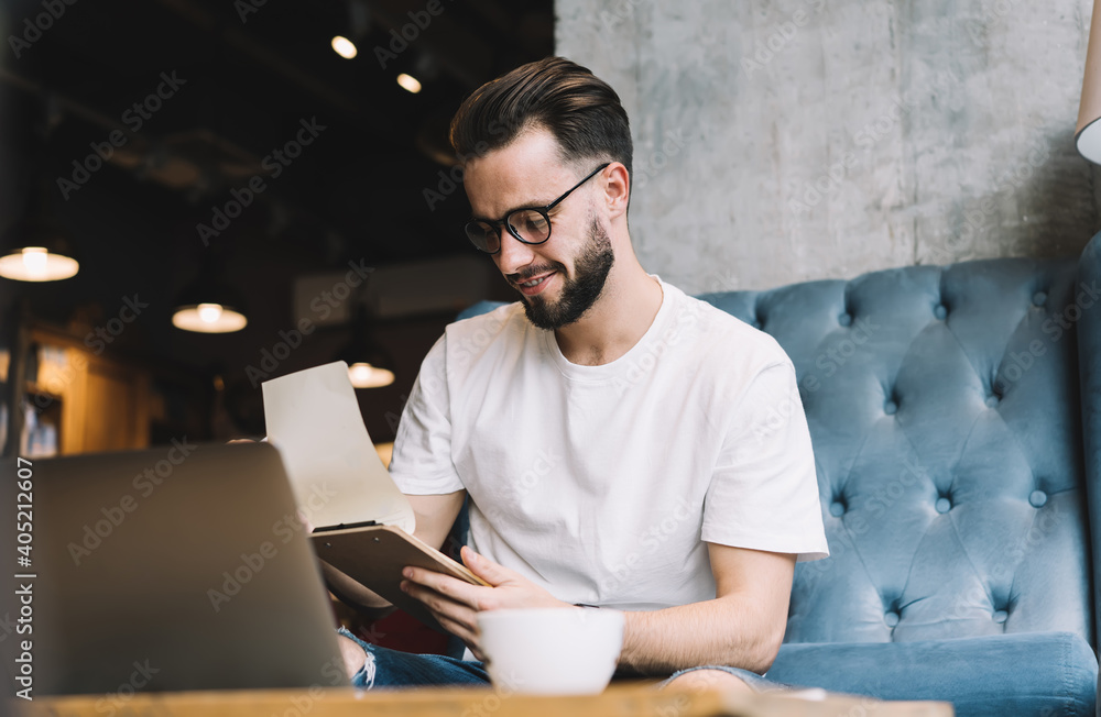 Poster smiling male student reading informative notes during time for knowledge studying and exam preparati