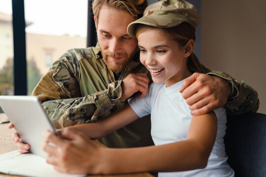 Masculine happy military man using tablet computer with her daughter