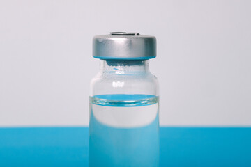 Coronavirus vaccine. New vaccine for covid-19. Glass bottle with liquid on a blue background. Covid-19, 2019-nCov pandemic.