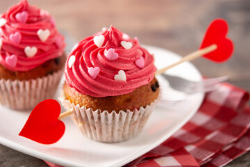 Cupcake decorated with sugar hearts and a cupid arrow for Valentine's Day on wooden table	

