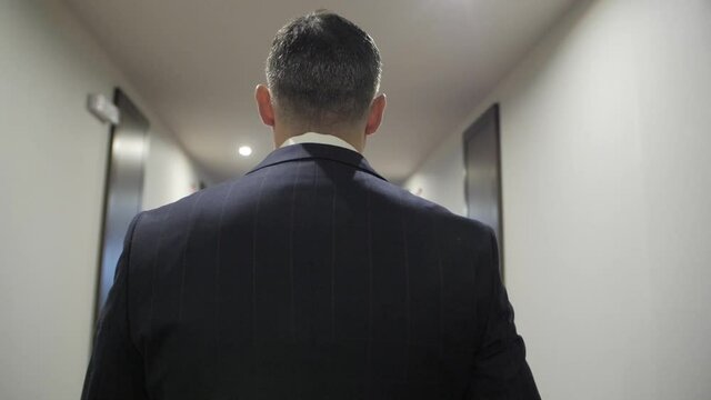 back view businessman wearing blue suit walking in office slow motion. manager at work