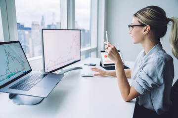 Female broker studying diagram on computer screen at work