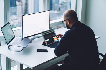 Anonymous trader analyzing data on tablet and computers in office