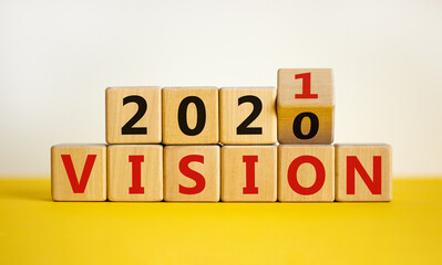 2021 vision symbol. Turned a wooden cube, changed words 'vision 2020' to 'vision 2021'. Beautiful yellow table, white background, copy space. Business, 2021 vision new year concept.