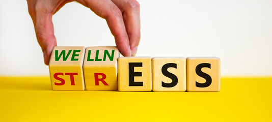 Wellness instead of stress symbol. Hand turns cubes and changes the word 'stress' to 'wellness'....