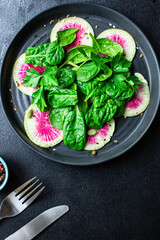Watermelon radish fresh salad chinese daikon Slices pink fruit, green leaves spinach lettuce on the table healthy meal snack top view copy space food background keto or paleo diet