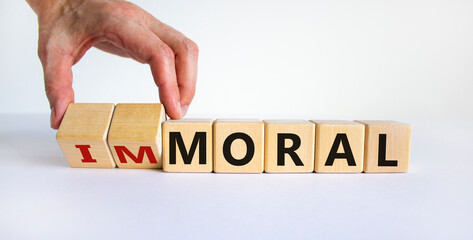 Moral or immoral symbol. Hand turns cubes and changes the word 'immoral' to 'moral'. Beautiful white background. Business and moral or immoral concept. Copy space.