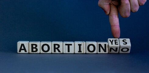 Abortion yes or no symbol. Male hand turns wooden cubes and changes words 'abortion yes' to...