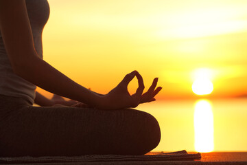 Woman silhouette doing yoga lotus pose at sunset