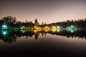 Obraz premium Night park, evening sky with stars. Park in city lake with refleNight park, evening sky with stars. Park in city lake with reflections on water. Sosnowiec, Polandctions in water. Sosnowiec, Poland