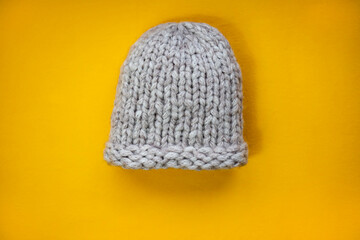 Warm knitted gray hat on a yellow background.