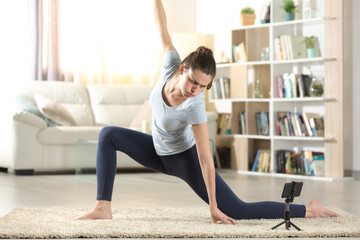 Woman learning yoga poses watching tutorial on phone