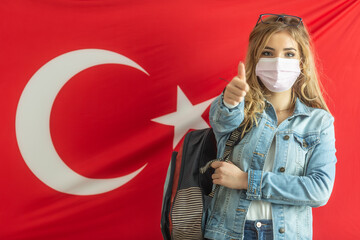 Thumbs up showing female blonde student stands in front of Turkish flag