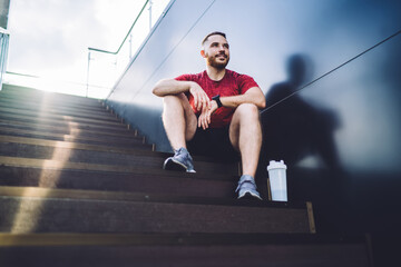 Thoughtful sportsman resting on stairs after workout