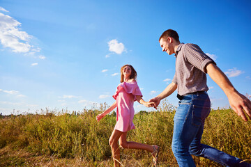 Fototapeta premium Shot of a young couple holding hands and running through the park.