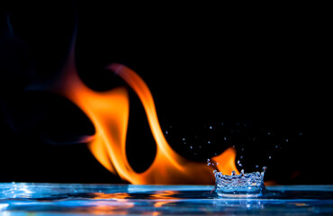Macro de gotas de agua salpicando contra un fondo de fuego - obrazy, fototapety, plakaty