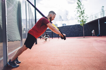 Obraz premium Active sportsman doing exercise with TRX straps