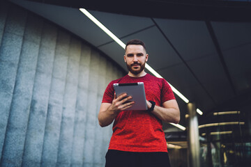 Confident male trainer using tablet