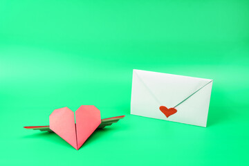 White envelope with red heart and red origami paper heart.