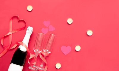 Valentine's day greeting card with champagne, glasses, valentines, candles, ribbon on a red background. Top view with place for text. Flat lay. copy space