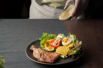 plate of delicious grilled chicken legs steak with vegetable salad on wooden table