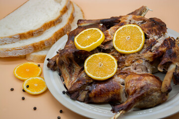 
Whole roasted chicken or duck on white plate, decorated with fresh oranges. Selective focus.