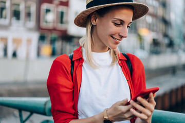 Smiling woman surfing cellphone during vacation in Europe