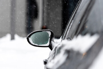 car covered with snow, close-up, selective focus, focus on the rear view mirror