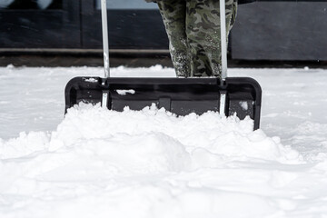 man cleaning snow with shovel in winter day