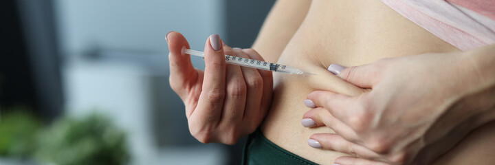 Woman making skin fold on stomach and injecting medicine from syringe at home. Continuous...
