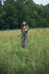 Woman on nature In a green jumpsuit, tall grass walk 