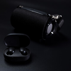 Black wireless eearphones. Wireless gadjets. Wireless speaker on black.