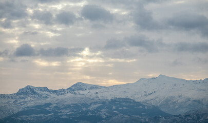 Naklejka na ściany i meble View of the highest peaks of Sierra Nevada (Granada, Spain) on a cloudy winter morning at sunrise