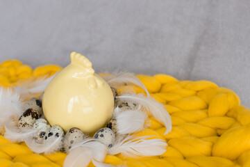 Easter composition of quail eggs and yellow ceramic chicken near a basket with yellow daffodils flowers
