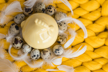 Easter composition of quail eggs and yellow ceramic chicken near a basket with yellow daffodils flowers