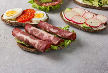 Open sandwiches on rye bread with cream cheese, ham, egg, radish, tomato.