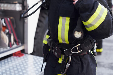 Female firefighter in protective uniform standing near truck